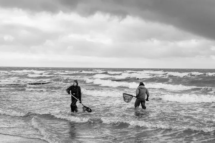 Bernsteinfischer mit Keschern in der Winterbrandung der Ostsee