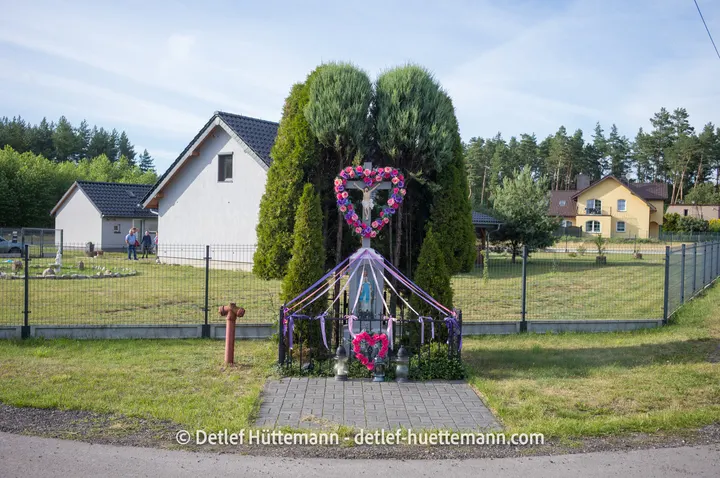 Christliches Wegekreuz mit Girlanden und Blumenschmuck in Tanina
