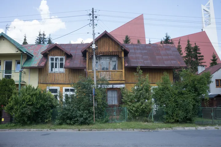 Altes Holzhaus, dahinter moderne Kirche in Krościenko nad Dunajcem