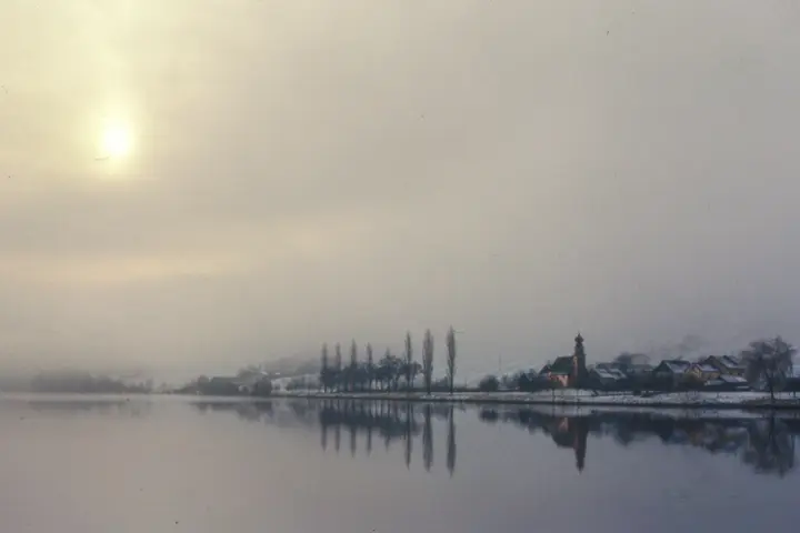 Wintermorgen am Fluss, Sonne im Dunst, Dorf mit Kirchturm spiegelt sich im Wasser, altes Farbdia
