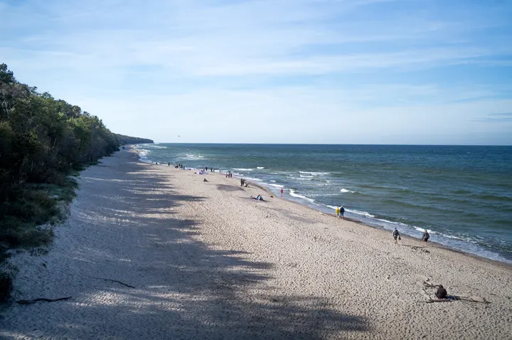 Breiter Sandstrand an der Ostsee, links bewaldete Steilküste