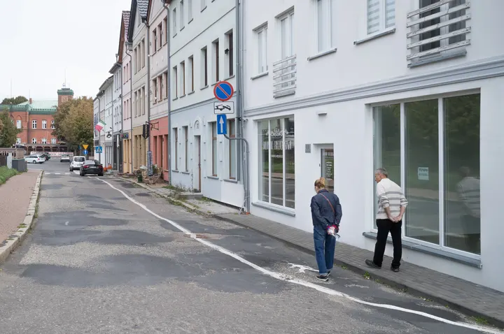 Straße mit Stadthäusern in Wolin, im Hintergrund ein Backsteinbau