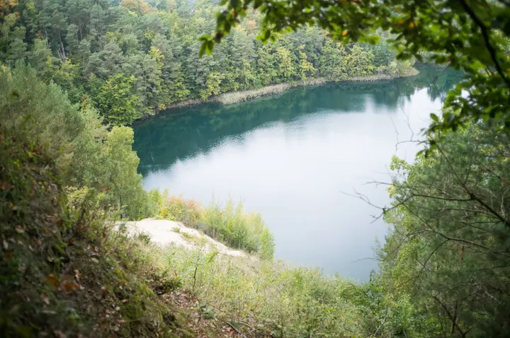 Türkisgrüner See zwischen bewaldeten Hängen, von oben gesehen