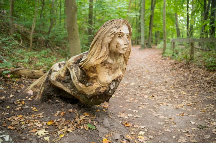 Holzskulptur eines Frauenkopfes am Waldweg