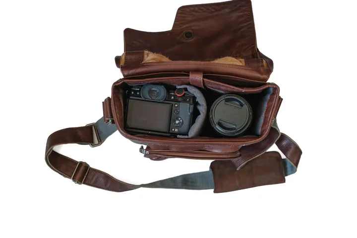 Geöffneter Compagnon Little Messenger aus braunem Leder mit Fuji X-T5 und einem Objektiv