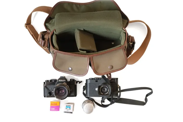 Geöffnete Billingham Hadley Small Pro, davor Nikon FM, Leica M, ein weiteres Objektiv sowie ein Farb- und ein Schwarzweißfilm