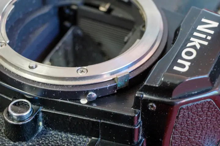 Bajonett der Nikon FM in Nahaufnahme: Der Ai-Kupplungshebel liegt flach am Ring, darunter der kleine weiße Entriegelungsknopf